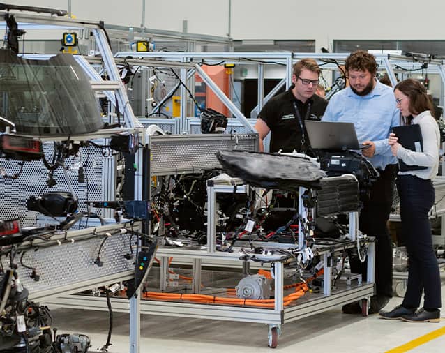 employees working on a machine in an automotive factory